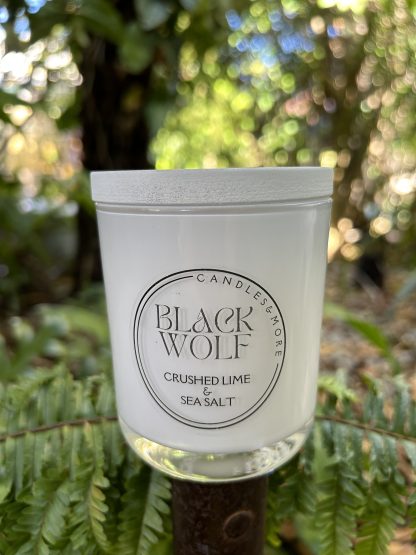 A white jar candle in a tropical garden setting